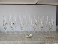 26 crystal champagne glasses including 6 decorated Perrier-Jouet glasses with floral design and a Perrier-Jouet coaster arranged on a marble surface.
