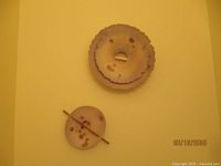 Two sand disc wall art pieces mounted on a yellow wall, showing their size difference and texture.