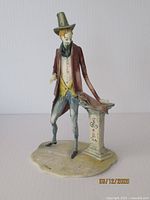 Front view of the painted ceramic figurine showing full figure and pedestal