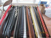 Belts laid out side by side showing overall variety in length, color and buckles.
