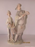 Full view of the porcelain figurine showing the town crier holding a scroll and the drummer boy with his drum and sticks, front view