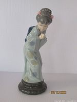Full front view of the Lladro Japanese Geisha figurine showing bowed position and floral kimono details.