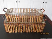 Two Pyrex glass baking dishes nested one on top of the other inside bamboo basket holders showing their size difference and natural bamboo handles.