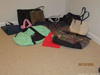 Overview of all totes and bags laid out on carpet showing a variety of styles and colors including black, beige, brown, pink, and green bags.