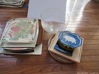 Various trays including silver tone rectangular and round trays, plastic tray with flamingos, Otagiri lacquerware tray with bird and foliage design, small wooden tray, and clear glass trifle bowl.