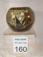 Small rounded stoneware vase with mottled cream and brown glaze, hand-painted with iron-based floral motifs.