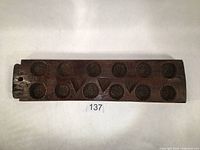 Top-down photo of the wooden mold showing the full length with floral and triangular carved shapes in a row.