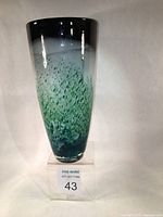 Photo of blown glass vase green cream black pattern with clear overlay from the front on clear stand