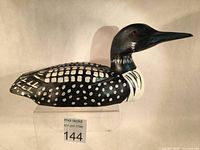 Front and side view of a hand carved and painted Common Loon decoy sculpture, showing detailed black and white pattern, glass eyes, and overall shape and size.