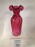 Front view of the cranberry glass vase showing the overall shape, ruffled three-lobed top, and swirl pattern throughout the body.