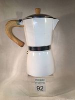 Front side view of white cast aluminum moka coffee maker with wooden-tone handle and knob.