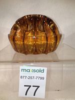 Front view of the brown amber glass flower frog showing its rounded shape and multiple holes for flowers.