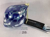 Side view of the hand blown glass ornament showing blue and white layered pattern and original label with tag.