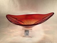 Full front view of the large ruby and clear Murano glass bowl, showing the translucent red color and elongated shape with rounded ends.