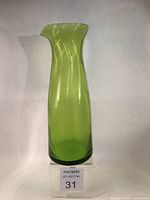 Tall green glass pitcher with spiral texture viewed frontally showing spout and body shape.