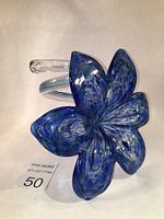 Top angled view showing the lily flower petals in blue with swirling clear and silver flakes on a curly clear stem.