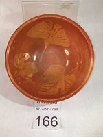 Top view of stoneware bowl showing wax resist leaf pattern on reddish-orange base.