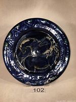 Full view of round ceramic plate with horse motif and cobalt blue glaze