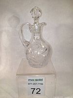 Front view of crystal cruet showing handle, stopper, and cut glass design.