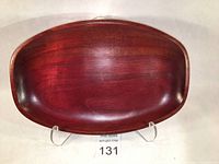 Top angled view of the vintage oval wooden tray showing the deep red wood grain and smooth finish.
