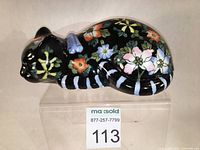 Sleeping cat porcelain figurine with black base glaze and colorful floral famille rose enamels from side angle