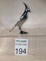 Front right side view of the aluminum Blue Jay sculpture showing its polished reflective surface and slender form.