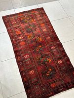 Full view of the small Persian runner rug placed on tiled floor, showing entire woven pattern and colors.