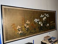 Front view of the full four-panel floral artwork in black frame hung on the wall.