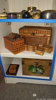 Full view of wooden shelves displaying various decorative wood boxes including large woven box with beetle, painted box with floral motif, and smaller boxes.