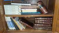 Shelf with multiple Jewish religious and cultural books including the 5-volume Lessons In Tanya set and various hardcover books with some wear visible