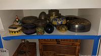 Shelf with assorted trinket boxes in various shapes, materials, and designs, including painted and metal boxes