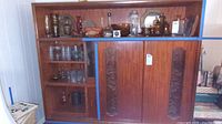 Wide view of wooden shelving unit holding glassware, vases, candle holders, bowls, metal trays, and other decorative items