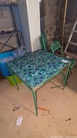 Photo showing vintage folding metal card table with floral print vinyl top and matching folding chairs with green metal frame and floral vinyl seats.