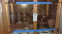 Photo showing a full cabinet display of pink Arcoroc Luminarc glassware including various dish types and pitchers.