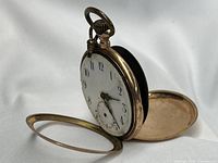 Pocket watch with front and back covers open resting on fabric