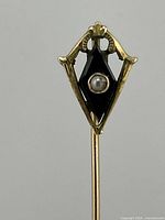 Front view of the gold lapel pin showing black onyx and pearl seed details.