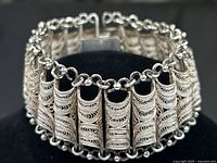 Front view of bracelet on black stand showing silver filigree segments and chain detail