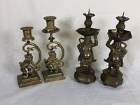 Group of four brass candlesticks (two lion motif, two Chinese figure motif)