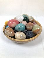 Wooden bowl filled with polished stone eggs of various colors