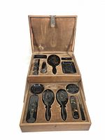 Open wooden box showing upper and lower compartments with tortoiseshell dresser set pieces arranged inside including mirrors, brushes, dishes and grooming tools.