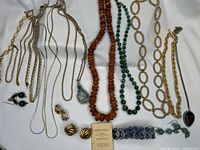 Full assortment of jewelry laid out on white fabric showing all items including necklaces, bracelets, earrings, and boxed Danish Amber bead necklace.