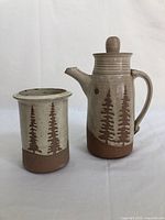 Front view showing both the jug with lid and the matching vase with tree motif design.