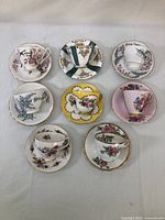 Top-down image showing eight teacups on their saucers arranged in rows, various floral patterns and colors visible