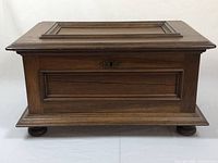 Front view showing the overall shape, paneling, and feet of the vintage wooden box.