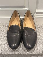 Front view of the black leather Chloe loafers showing scalloped edge detail and toe area.