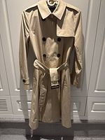 Front view of the full khaki trench coat showing double-breasted button design, collar, belted waist, and length.