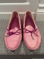 Front angle view of the pink textured leather driving loafers with lace bow detail.