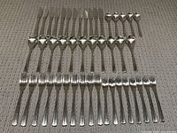 Full view of the cutlery set arranged by item type on a gray textured fabric surface.