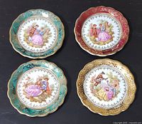 Four miniature plates displayed with scalloped edges and colorful gold-accented rims, featuring romantic Fragonard-style scenes.