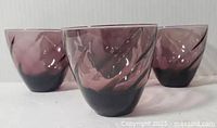 Four 1960s Hazel Atlas amethyst swirl pattern beverage tumblers displayed showing front and side views.